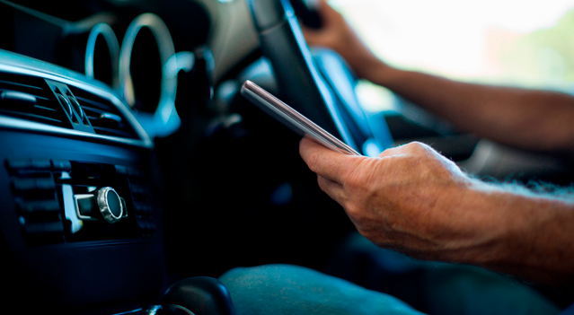 Condcutor verificando mensajes al manejar