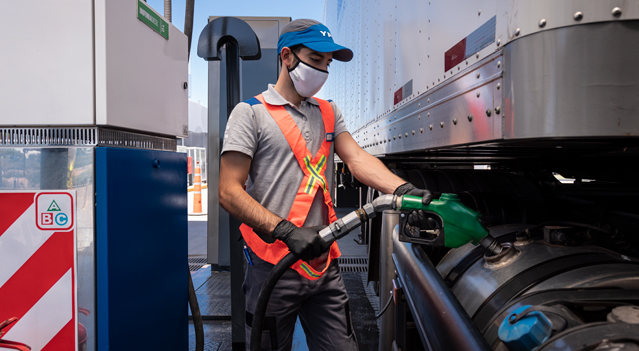 Personal de estación de servicio realizando una carga de combustible para un vehículo